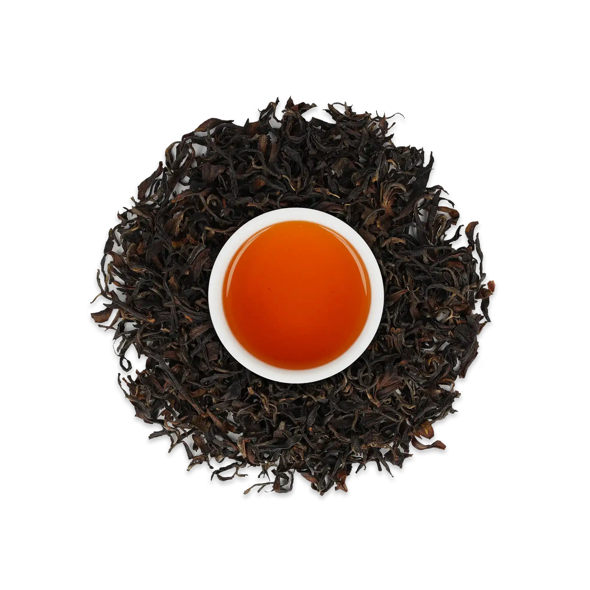 Weiße Keramiktasse mit leuchtend orange-braunem Schwarztee, umgeben von losen schwarzen Teeblättern.