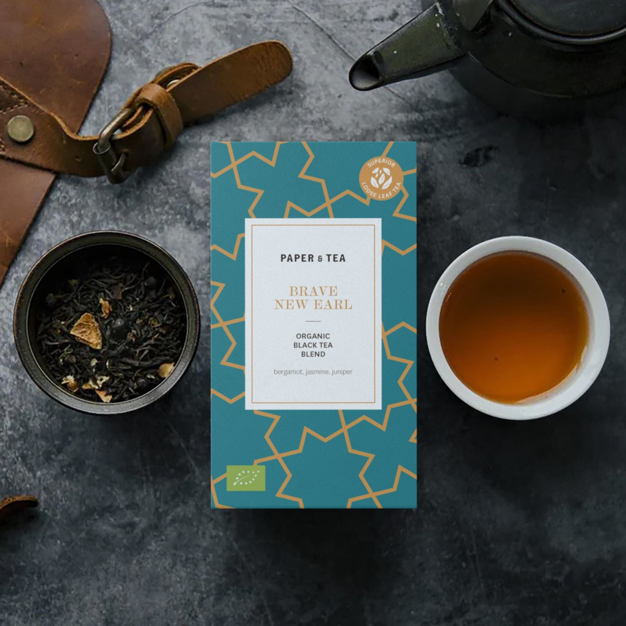 Kasten organischer BRAVE NEW EARL Schwarztee von PAPER & TEA mit Bergamotte, lose Blätter und Tasse Tee.