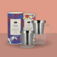 Drei farbenfrohe, zylindrische Teedosen mit Mustern und zwei doppelwandige Glas-Tee-Becher mit Infusoren.