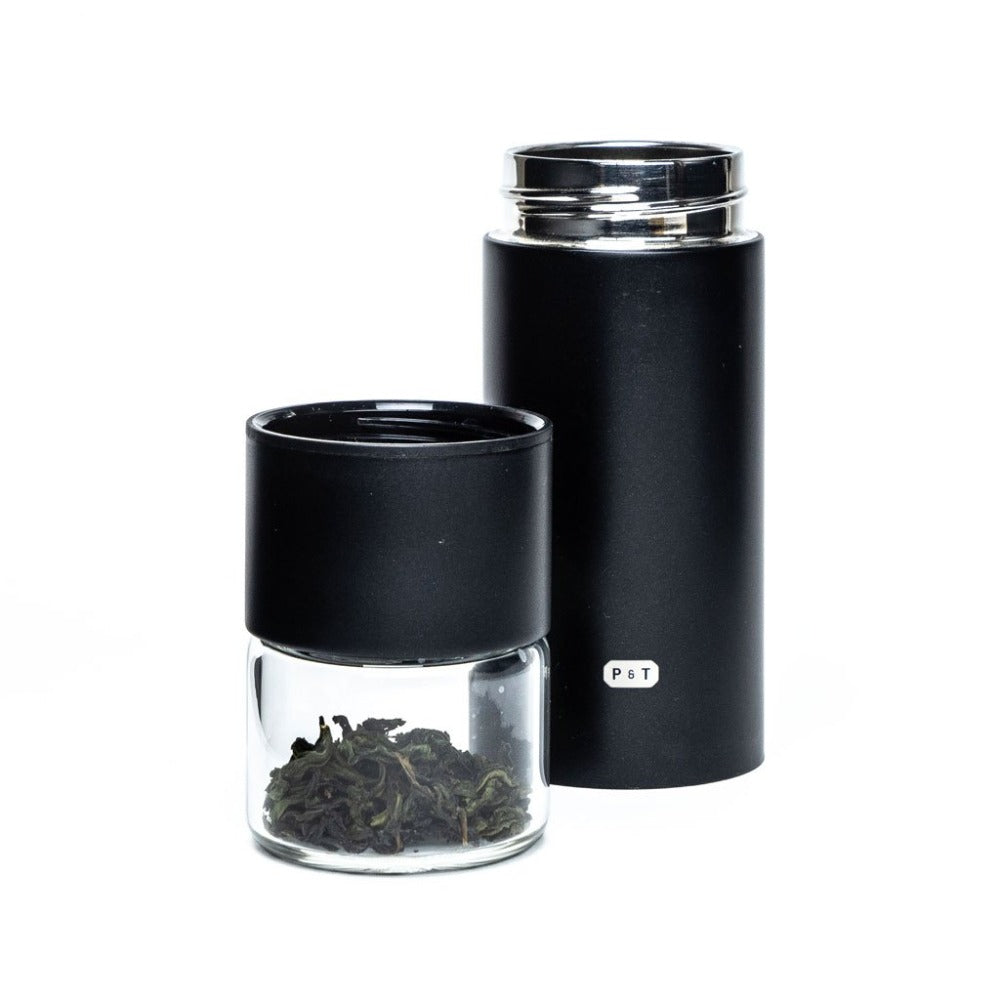 Moderne schwarze Teebehälter von P & T, matte Zylinderform, daneben Dose mit getrockneten Teeblättern