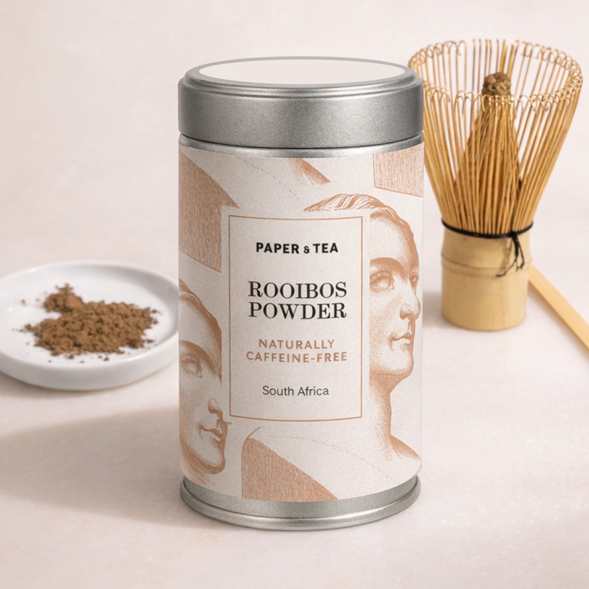 Metallbehälter mit P&T Rooibos-Pulver aus Südafrika, links Schale mit Pulver, rechts Bambusbesen