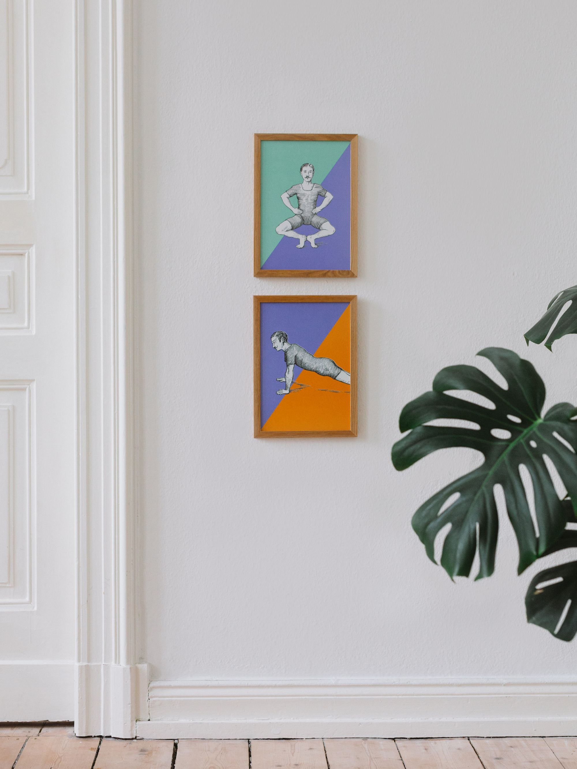 Minimalistische Ecke mit weißer Tür, großer Monstera und zwei gerahmten Vintage-Illustrationen an der Wand.