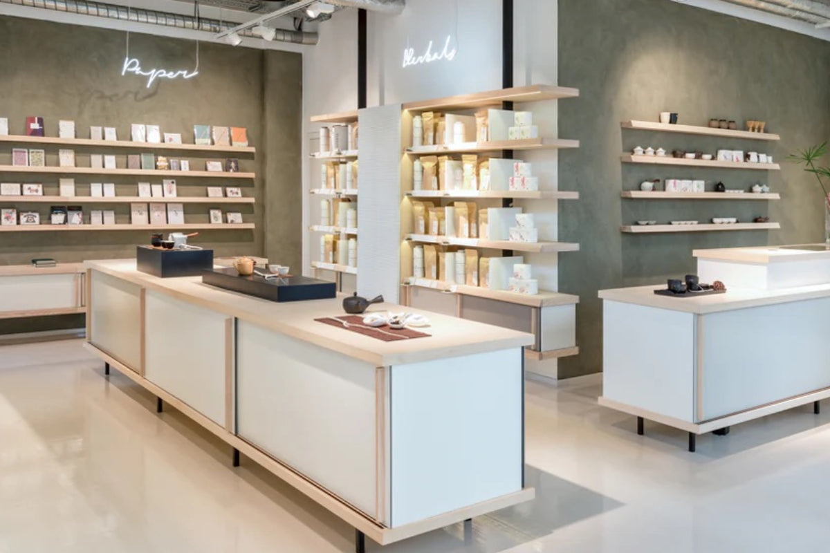 Einzelhandelsladen mit Papierwaren unter Neonlicht 'Paper' und Hautpflegeprodukten auf Holzregalen.