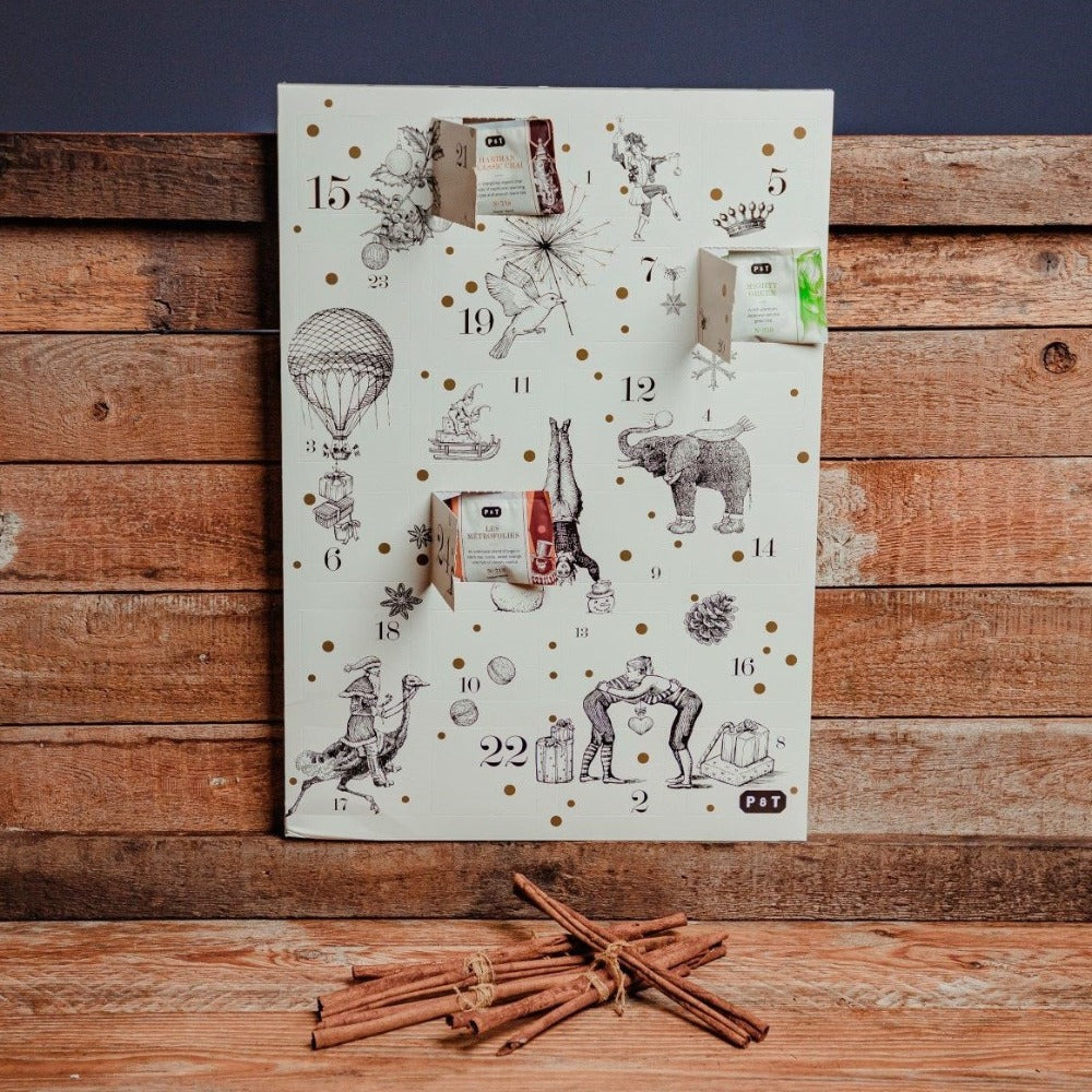 Weißer Adventskalender mit Vintage-Illustrationen, goldenen Punkten, Teebeuteln und Zimtstangen.