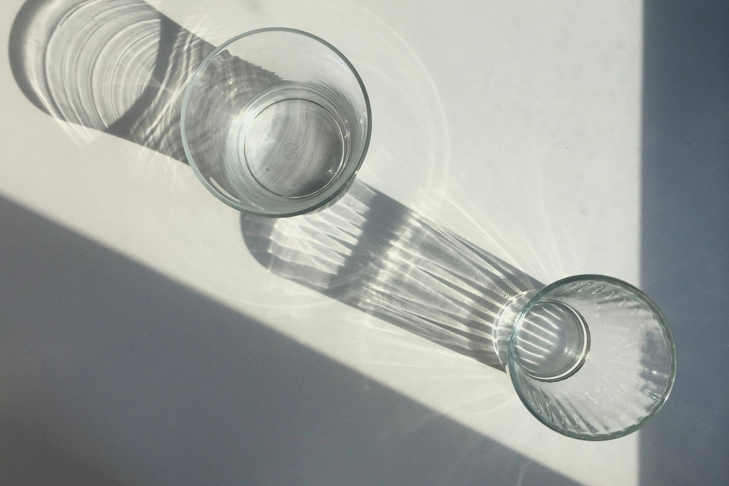 Zwei transparente Gläser von oben auf einem weißen Tisch stehend