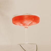 Elegantes Cocktailglas mit langem Stiel und leuchtend rotem Getränk, dekorativer Glasrand.