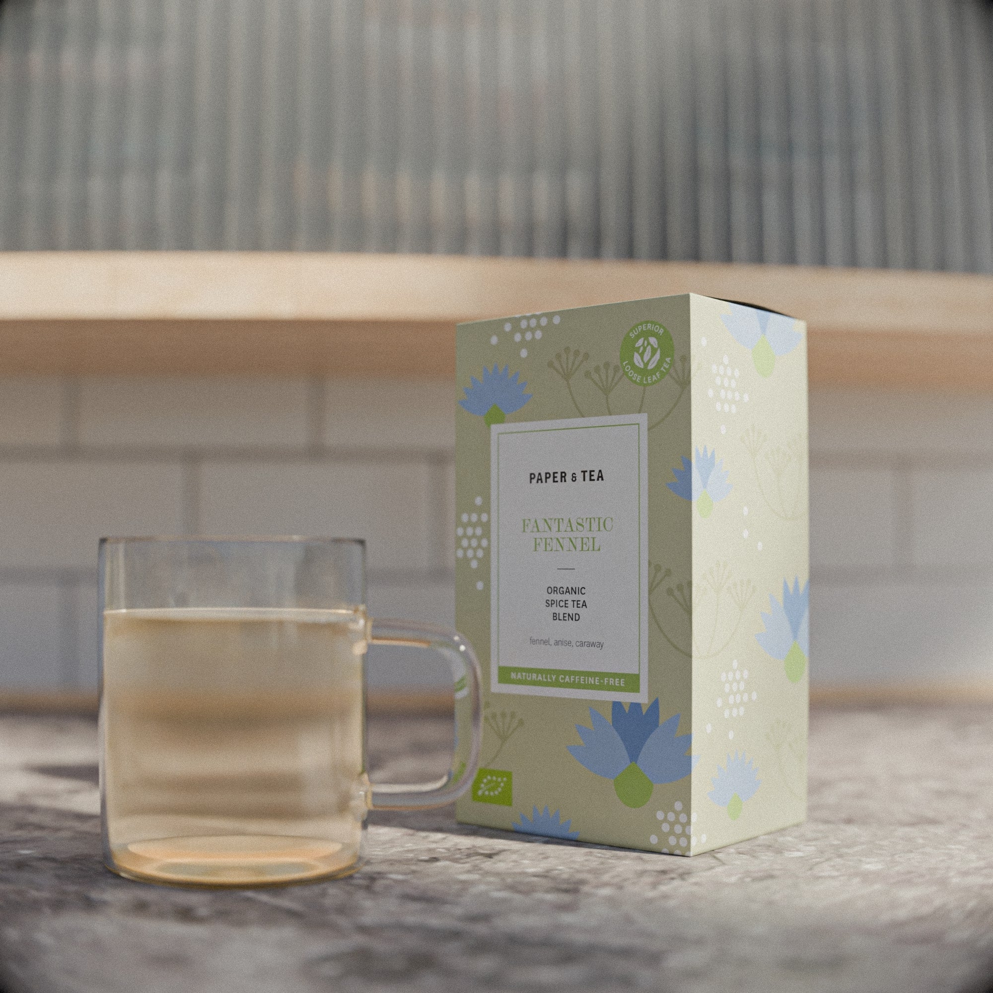 Verpackung von Bio-Fencheltee von Paper & Tea neben einem Teeglas auf Küchenarbeitsplatte.