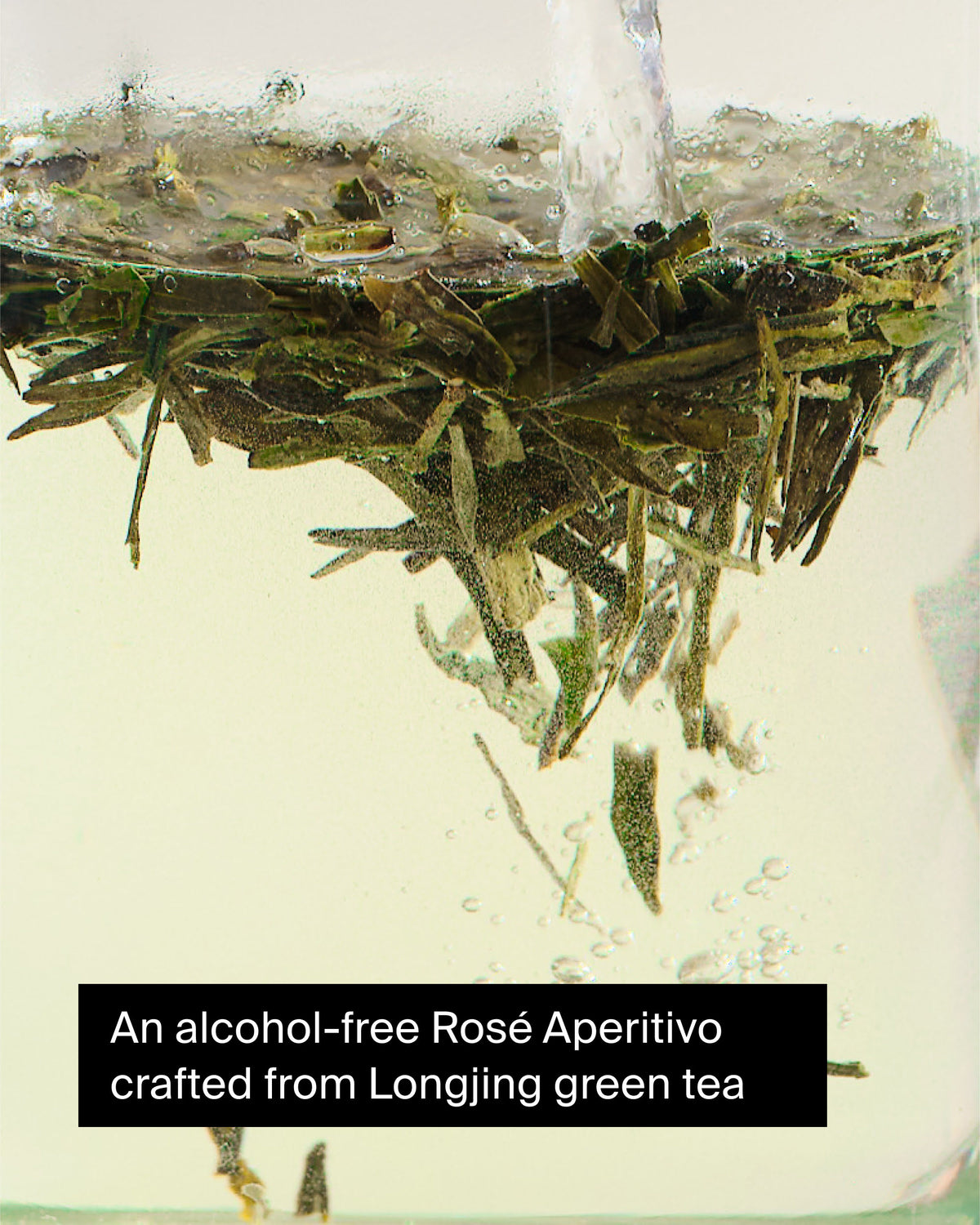 Nahaufnahme von Longjing-Grünteeblättern mit aufsteigenden Bläschen in alkoholfreiem Rosé-Aperitivo.